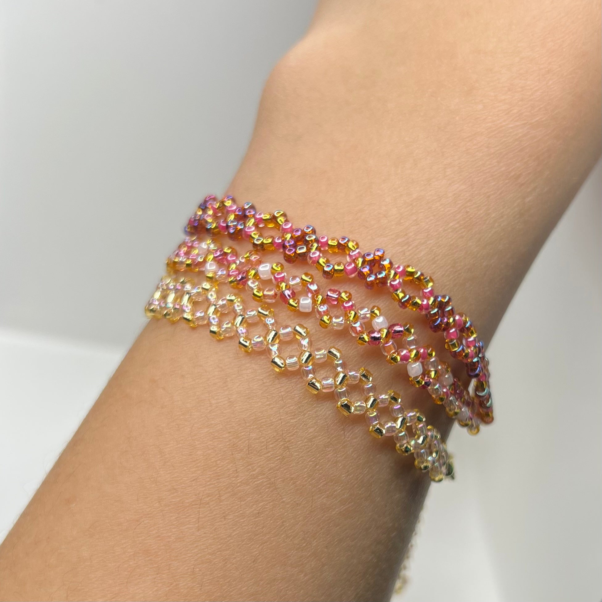 Multicolored beaded bracelet on a wrist against a neutral background
